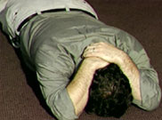 image of man lying face down with hands covered his head