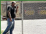 image of man standing looking behind a fence